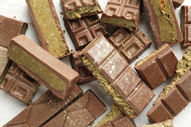 Pieces of tasty Dubai chocolate with pistachios and knafeh on white table, top view