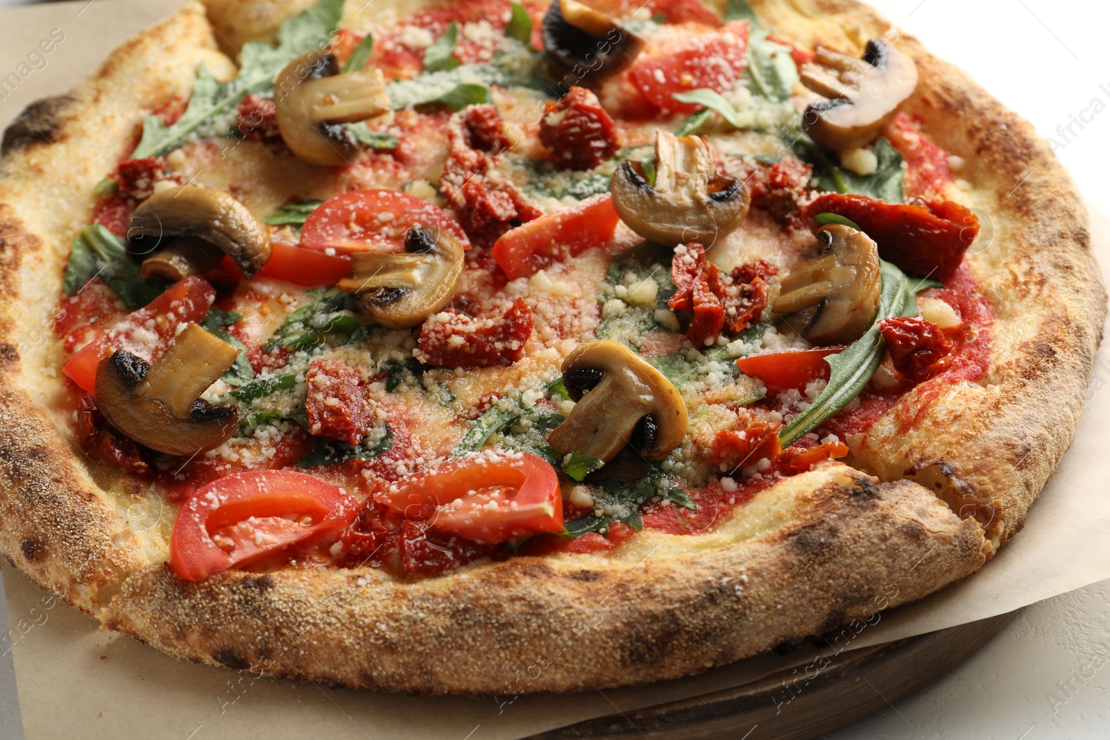 Photo of Tasty pizza with mushrooms, tomatoes and arugula on white table, closeup