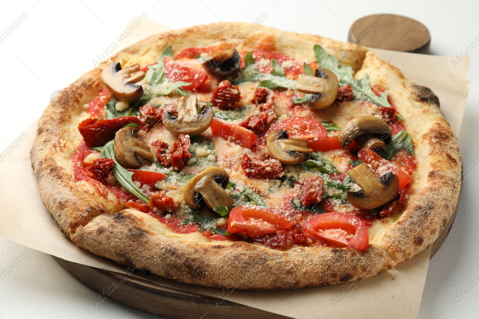 Photo of Tasty pizza with mushrooms, tomatoes and arugula on white table, closeup