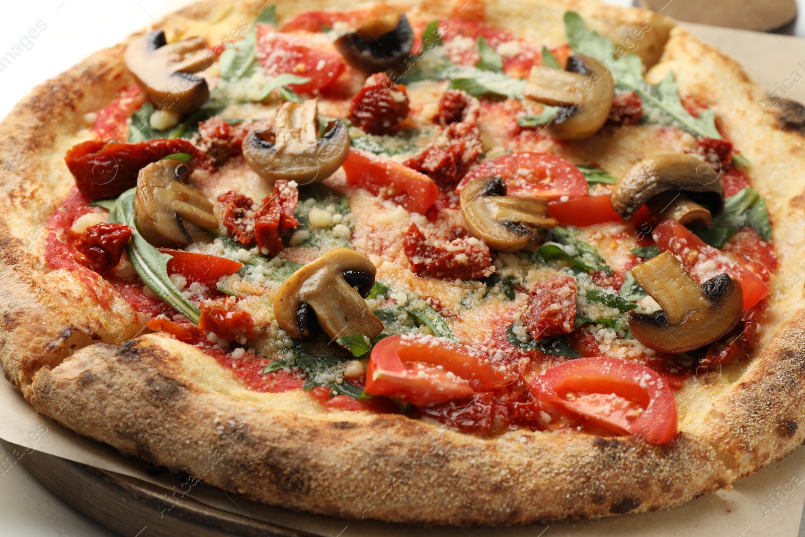 Photo of Tasty pizza with mushrooms, tomatoes and arugula on table, closeup