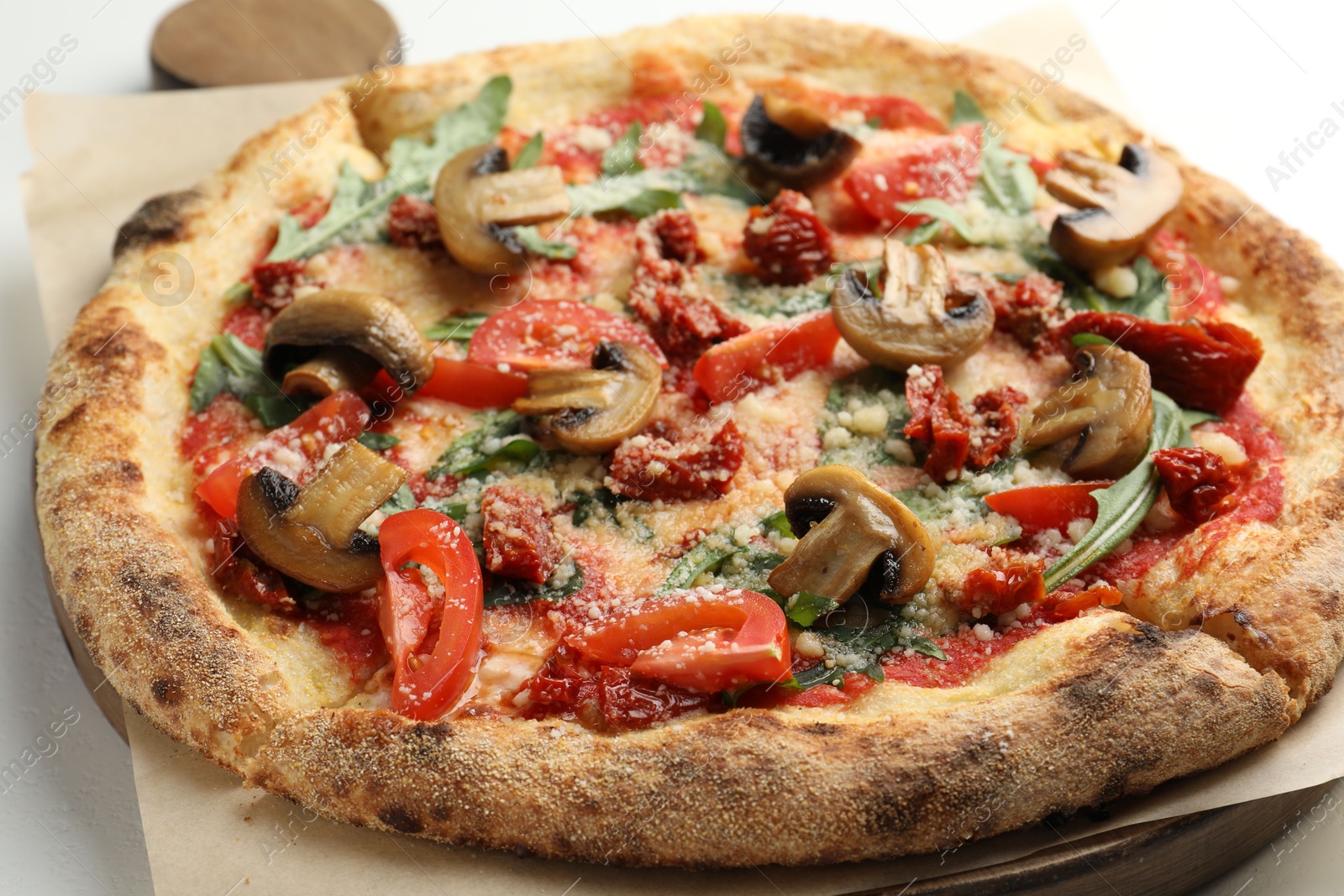 Photo of Tasty pizza with mushrooms, tomatoes and arugula on white table, closeup