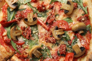 Tasty pizza with mushrooms, tomatoes and arugula as background, top view