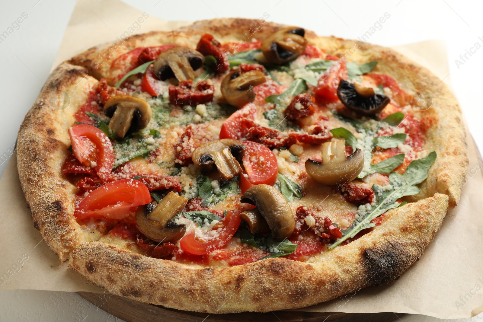 Photo of Tasty pizza with mushrooms, tomatoes and arugula on white table, closeup