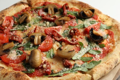 Photo of Tasty pizza with mushrooms, tomatoes and arugula on white table, closeup