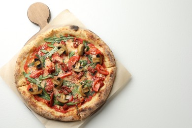 Tasty pizza with mushrooms, tomatoes and arugula on white table, top view. Space for text