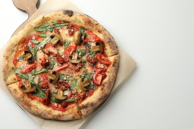 Tasty pizza with mushrooms, tomatoes and arugula on white table, top view. Space for text