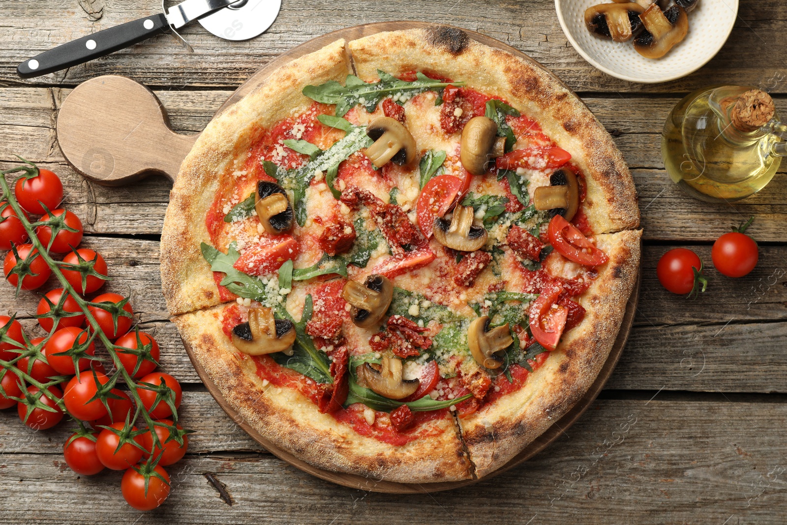 Photo of Tasty pizza with mushrooms, arugula and tomatoes on wooden table, flat lay