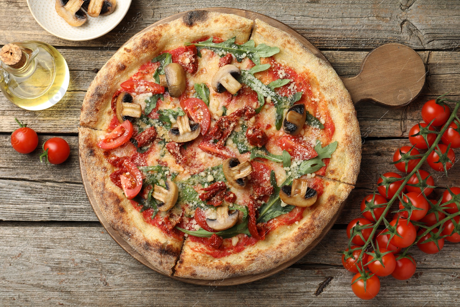 Photo of Tasty pizza with mushrooms, arugula and tomatoes on wooden table, flat lay