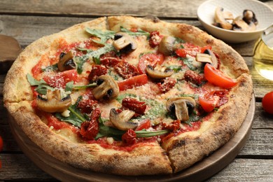 Photo of Tasty pizza with mushrooms, tomatoes and arugula on wooden table, closeup