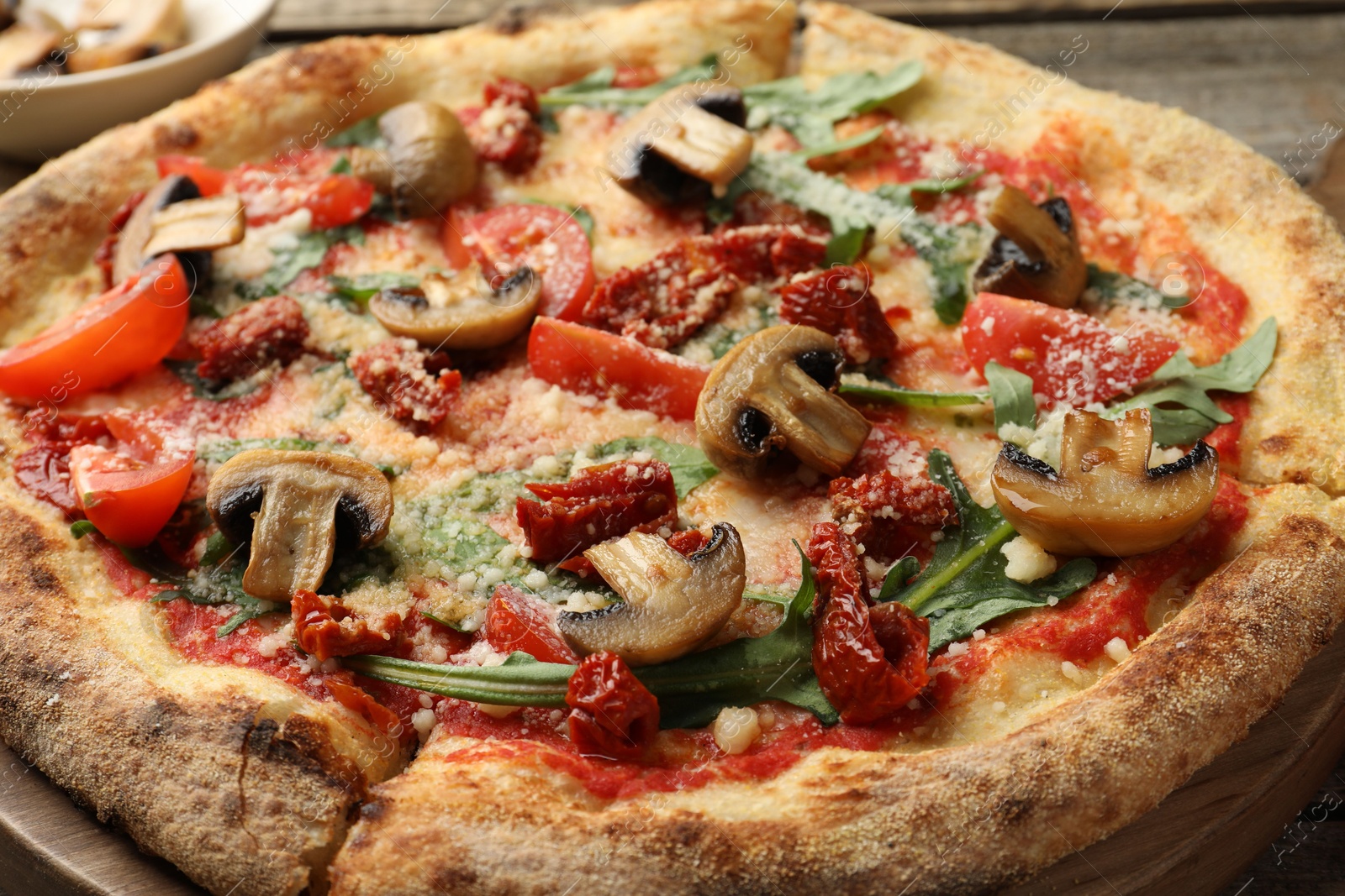 Photo of Tasty pizza with mushrooms, tomatoes and arugula on wooden table, closeup