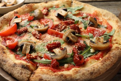 Tasty pizza with mushrooms, tomatoes and arugula on wooden table, closeup