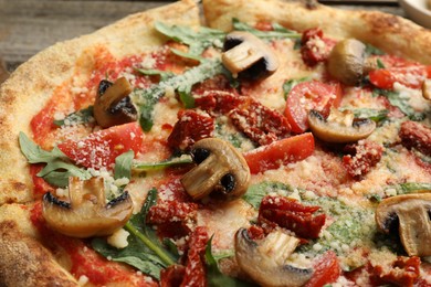 Tasty pizza with mushrooms, tomatoes and arugula on table, closeup