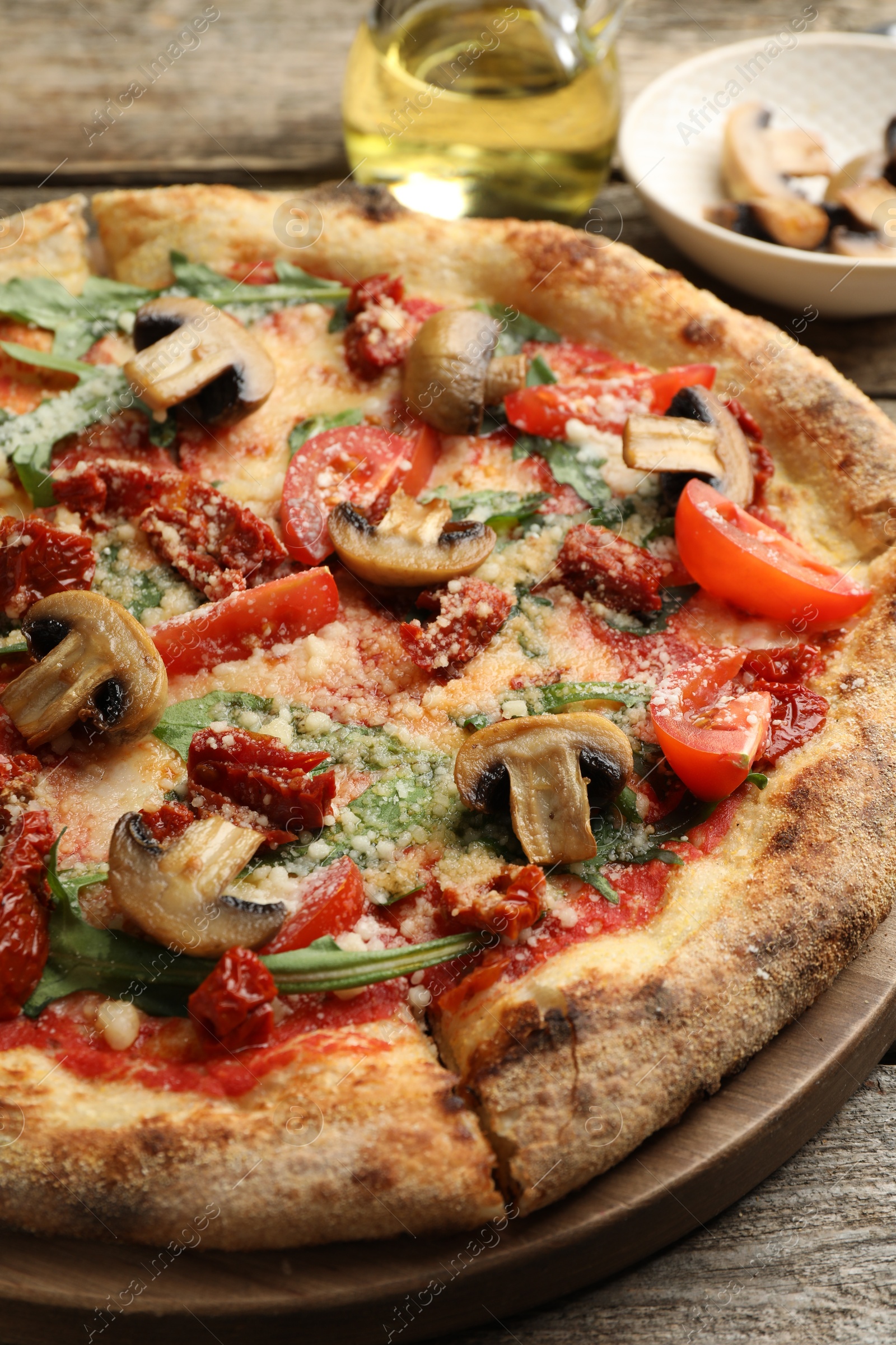 Tasty pizza with mushrooms, tomatoes and arugula on wooden table, closeup Photo of Tasty pizza with mushrooms, tomatoes and arugula on wooden table, closeup