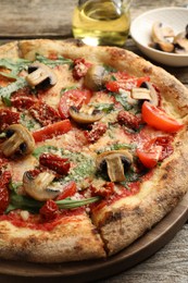 Photo of Tasty pizza with mushrooms, tomatoes and arugula on wooden table, closeup