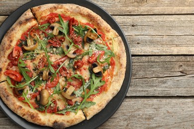 Photo of Tasty pizza with mushrooms, tomatoes and arugula on wooden table, top view. Space for text