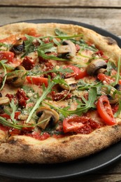 Tasty pizza with mushrooms, tomatoes and arugula on wooden table, closeup