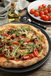 Tasty pizza with mushrooms, tomatoes and arugula served on wooden table, closeup