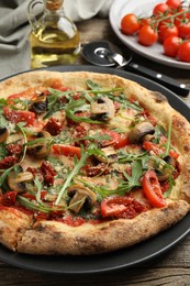 Photo of Tasty pizza with mushrooms, tomatoes and arugula on wooden table, closeup