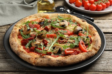 Tasty pizza with mushrooms, tomatoes and arugula on wooden table, closeup