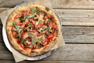 Photo of Tasty pizza with mushrooms, tomatoes and arugula on wooden table, top view. Space for text