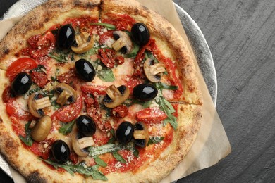 Tasty pizza with mushrooms, olives and arugula on black table, top view