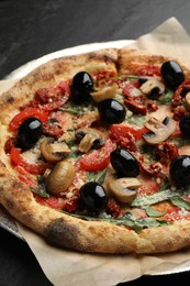 Photo of Tasty pizza with mushrooms, olives and arugula on black table, closeup