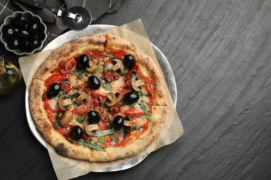 Tasty pizza with mushrooms, olives, arugula and cutter on black table, flat lay. Space for text