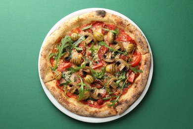 Photo of Tasty pizza with mushrooms, olives and arugula on green background, top view