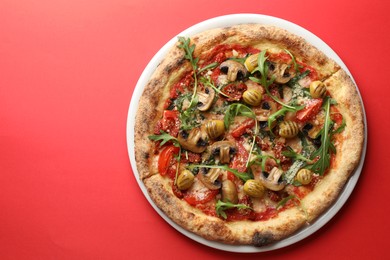 Tasty pizza with mushrooms, olives and arugula on red background, top view. Space for text