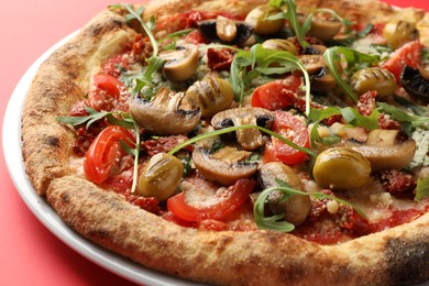 Photo of Tasty pizza with mushrooms, olives and arugula on red background, closeup