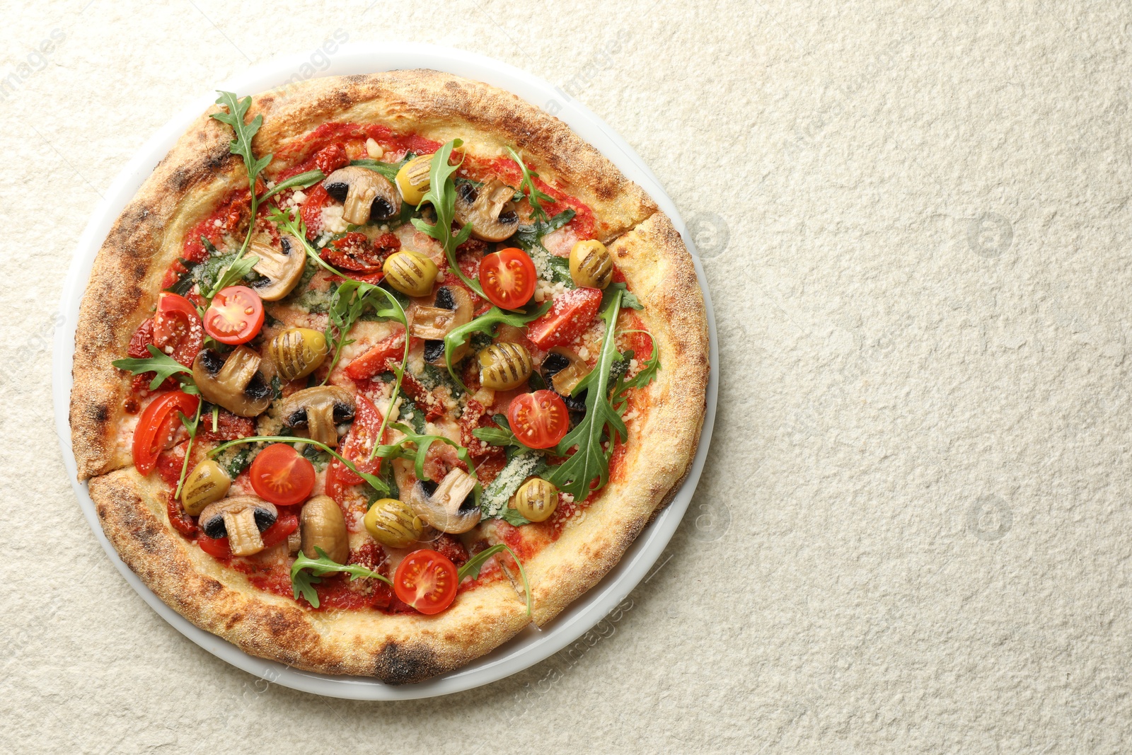 Photo of Tasty pizza with mushrooms, olives, tomatoes and arugula on white textured table, top view. Space for text