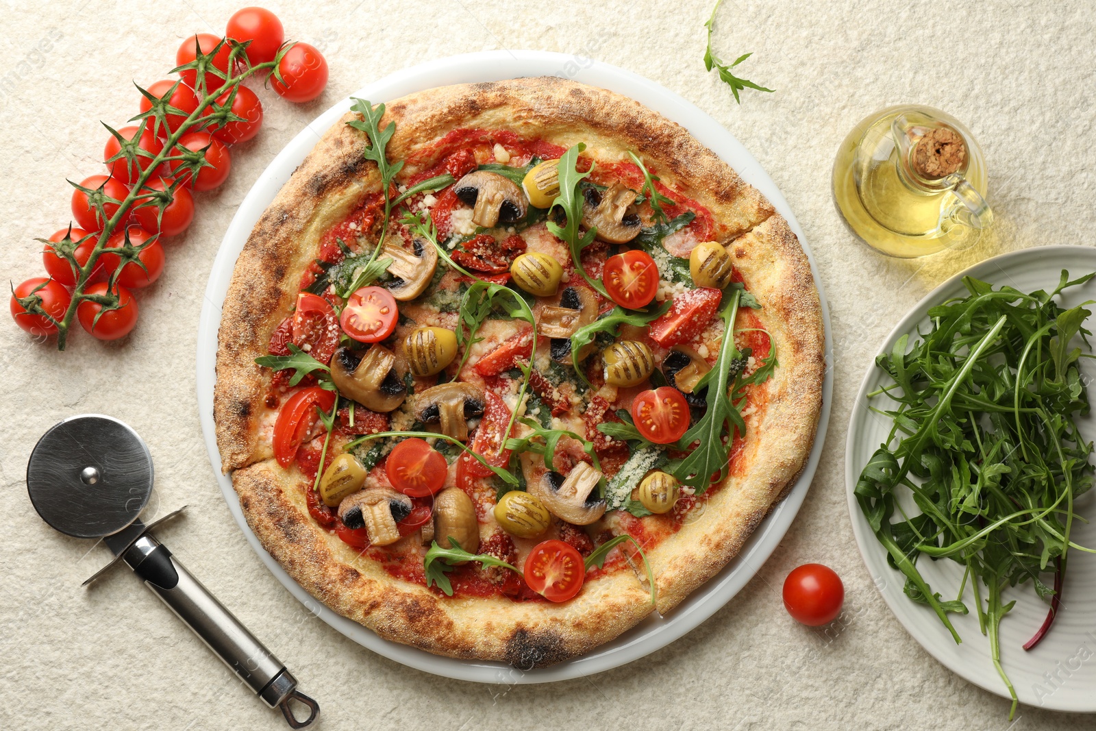 Photo of Tasty pizza with mushrooms, olives, tomatoes and arugula served on white textured table, flat lay