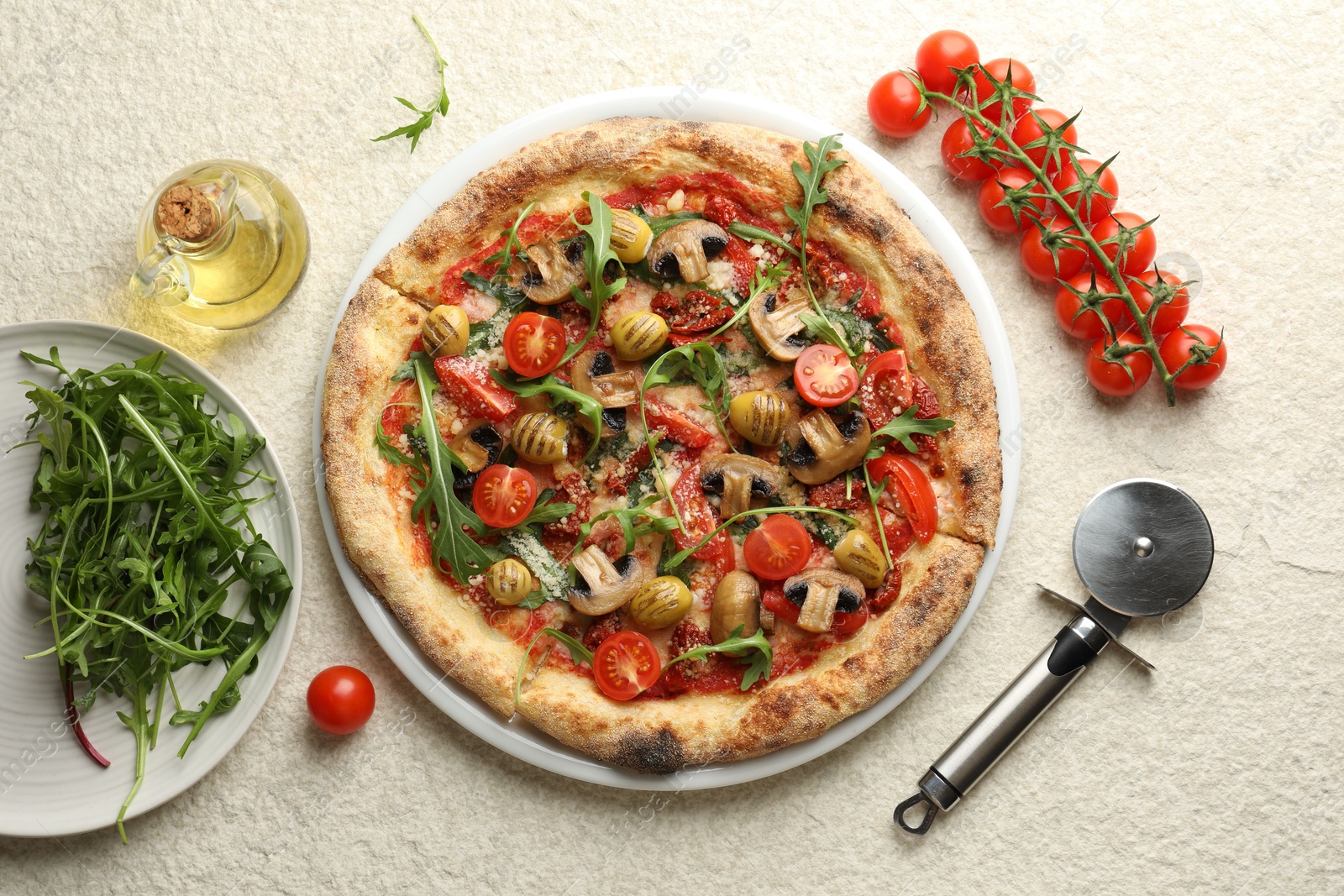 Photo of Tasty pizza with mushrooms, olives, tomatoes and arugula served on white textured table, flat lay