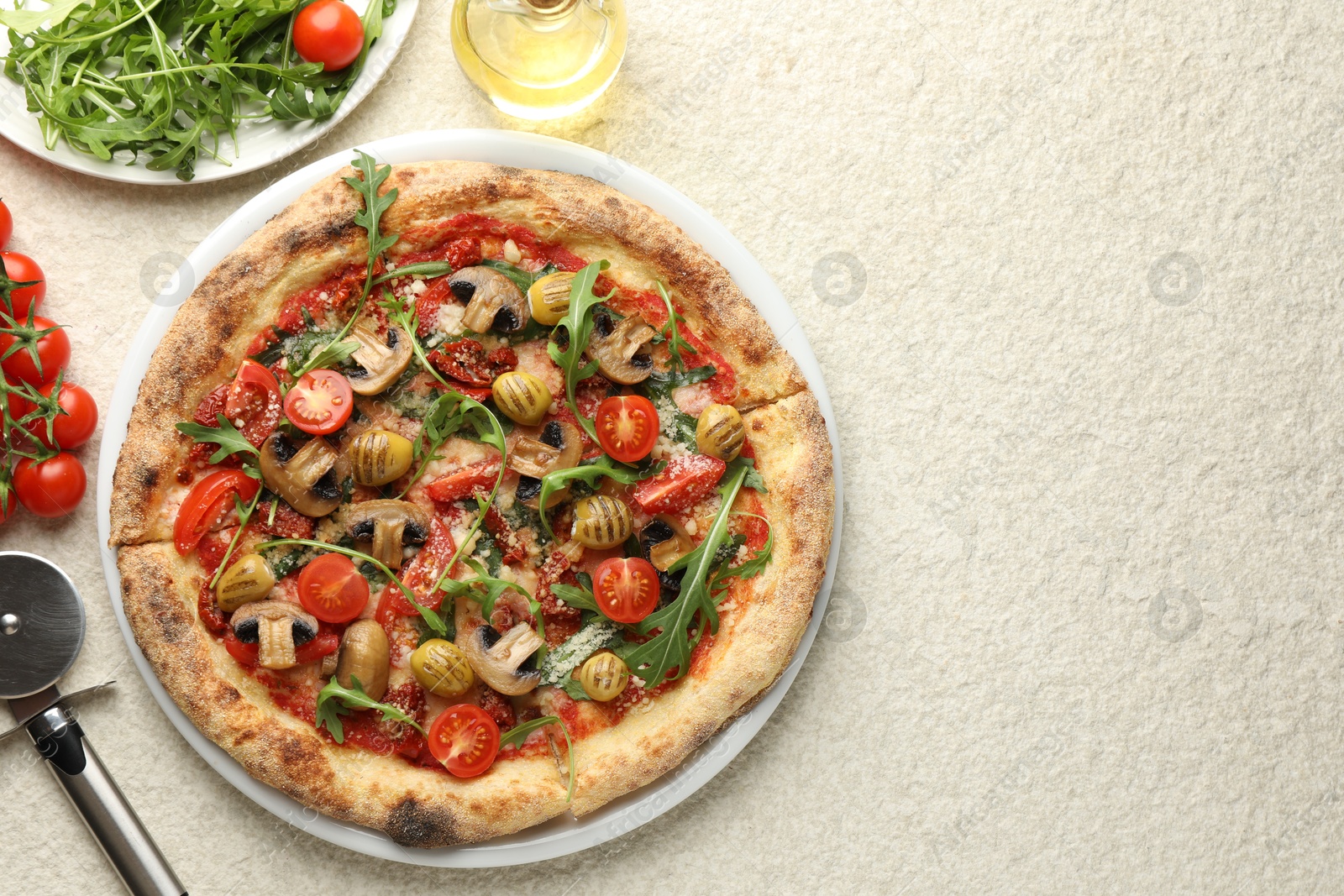 Photo of Tasty pizza with mushrooms, olives, tomatoes and arugula served on white textured table, flat lay. Space for text