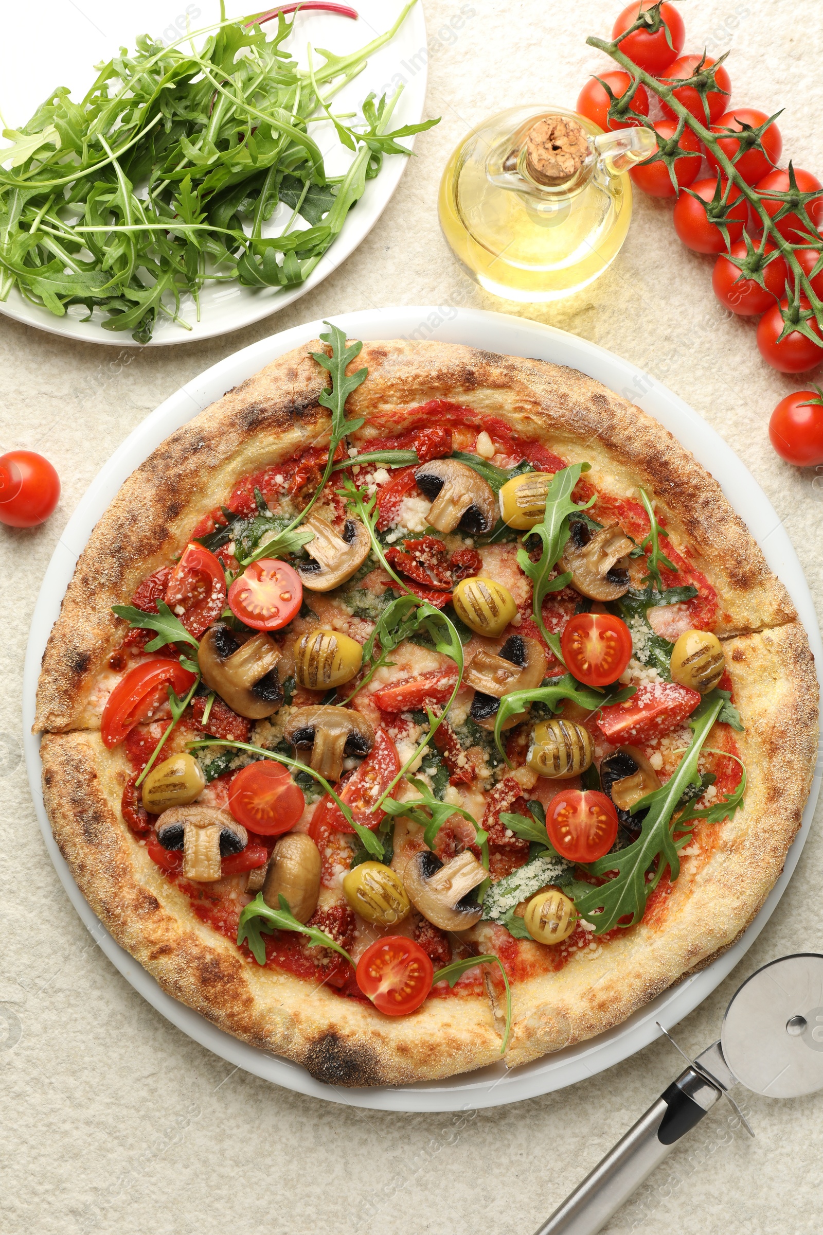 Photo of Tasty pizza with mushrooms, olives, tomatoes and arugula served on white textured table, flat lay