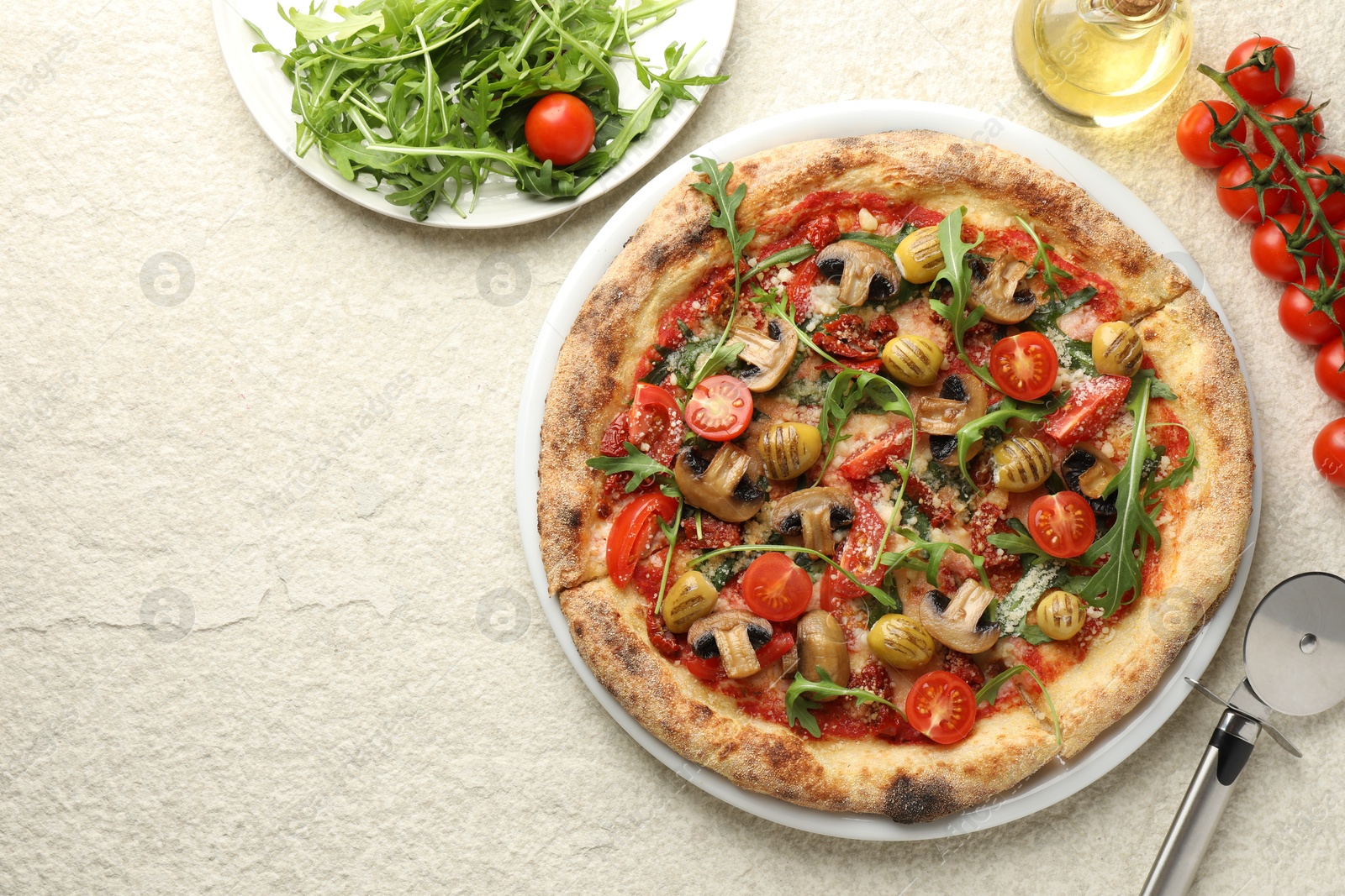 Photo of Tasty pizza with mushrooms, olives, tomatoes and arugula served on white textured table, flat lay. Space for text