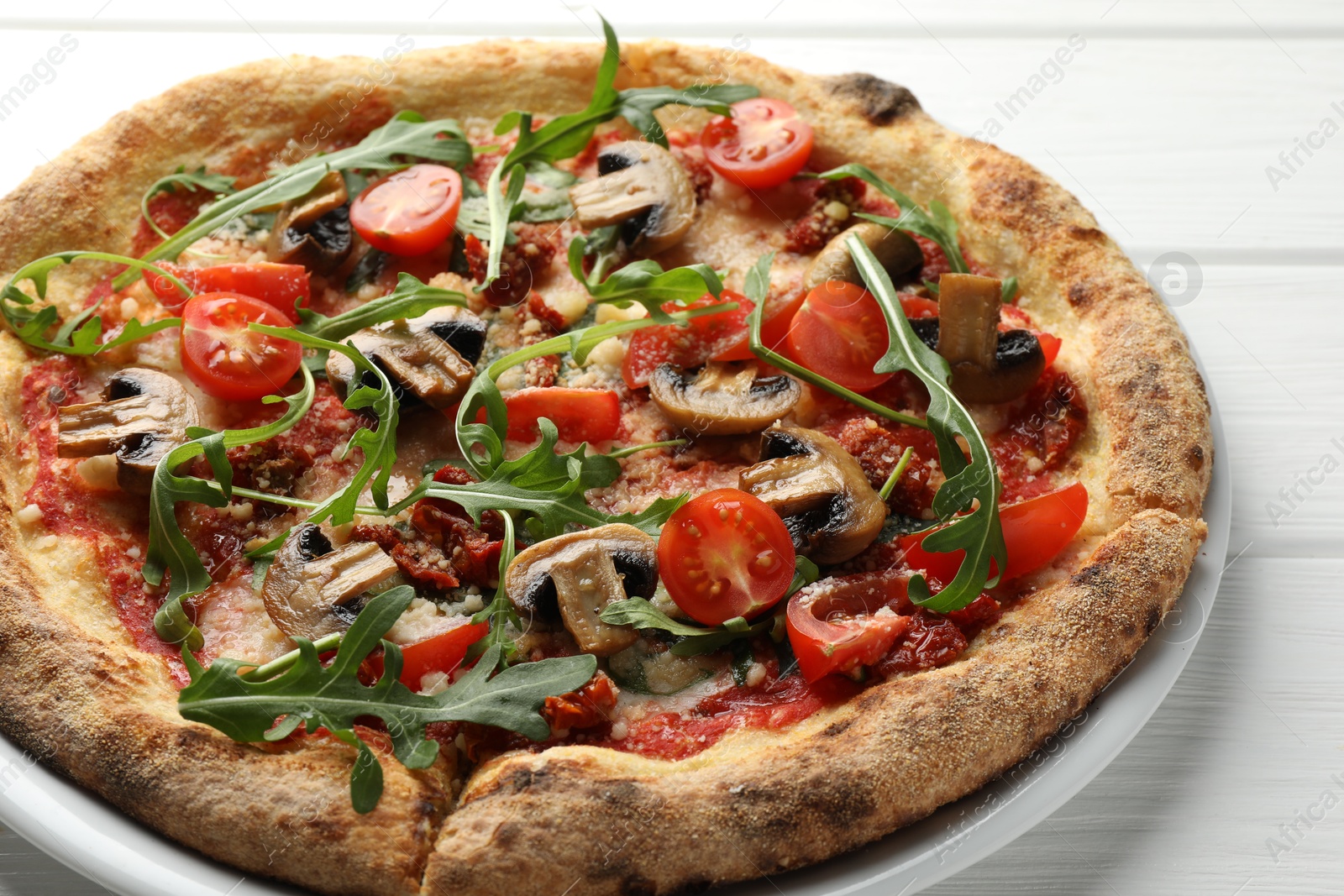 Tasty pizza with mushrooms, tomatoes and arugula on white wooden table, closeup Photo of Tasty pizza with mushrooms, tomatoes and arugula on white wooden table, closeup