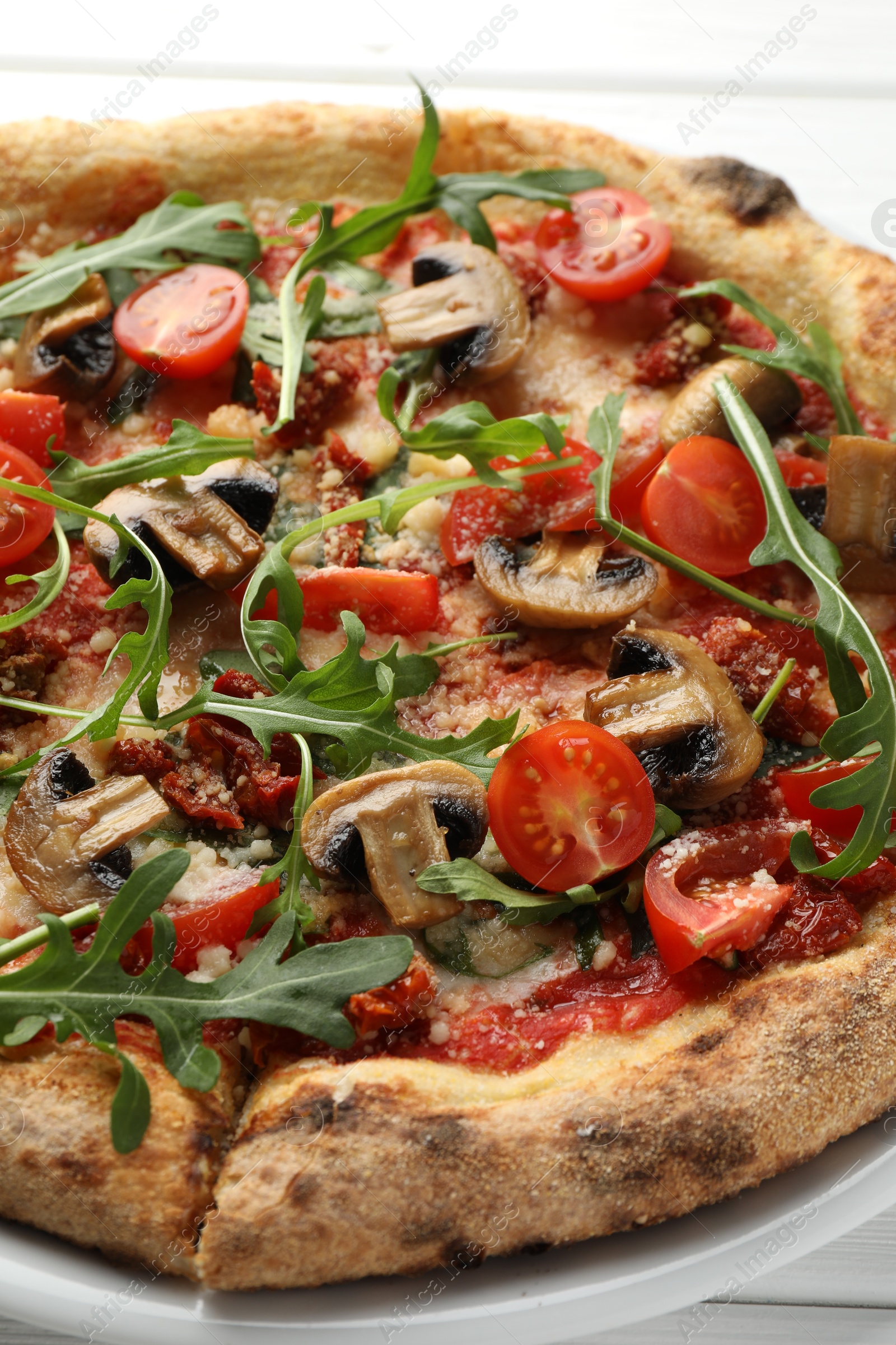 Tasty pizza with mushrooms, tomatoes and arugula on white table, closeup Photo of Tasty pizza with mushrooms, tomatoes and arugula on white table, closeup