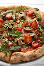 Photo of Tasty pizza with mushrooms, tomatoes and arugula on white table, closeup