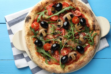 Photo of Tasty pizza with mushrooms, black olives and arugula on light blue wooden table, top view