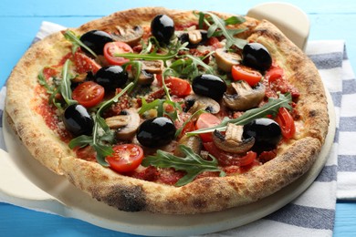 Tasty pizza with mushrooms, black olives and arugula on light blue wooden table, closeup