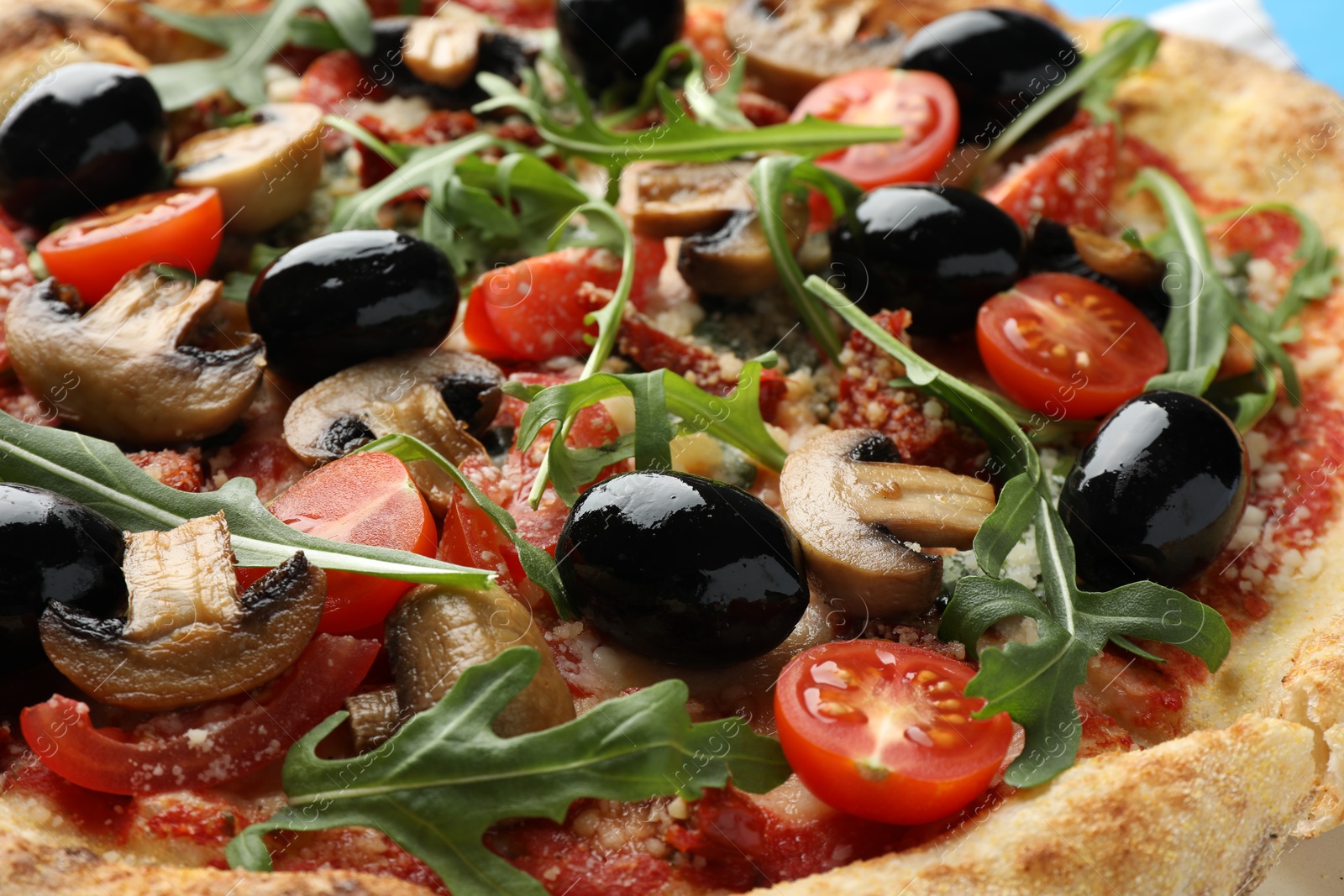 Photo of Tasty pizza with mushrooms, black olives and arugula, closeup