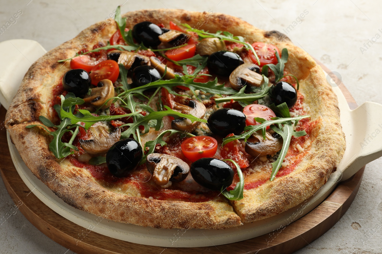 Photo of Tasty pizza with mushrooms, black olives and arugula on light grey table, closeup