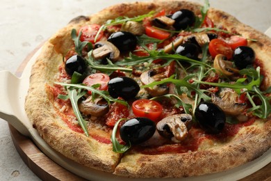 Tasty pizza with mushrooms, black olives and arugula on light grey table, closeup