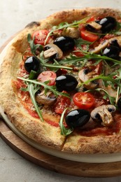 Tasty pizza with mushrooms, black olives and arugula on light grey table, closeup