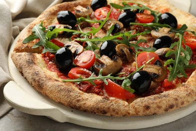 Tasty pizza with mushrooms, olives and arugula on light grey table, closeup