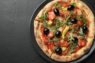 Photo of Tasty pizza with tomatoes, olives, chili and arugula on black table, top view. Space for text