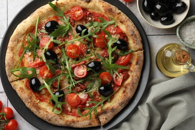 Photo of Tasty pizza with black olives, tomatoes and arugula on light tiled table, flat lay