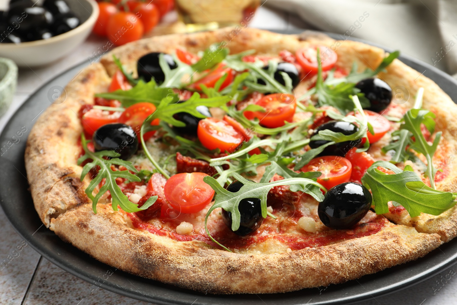 Photo of Tasty pizza with tomatoes, olives and arugula on light tiled table, closeup