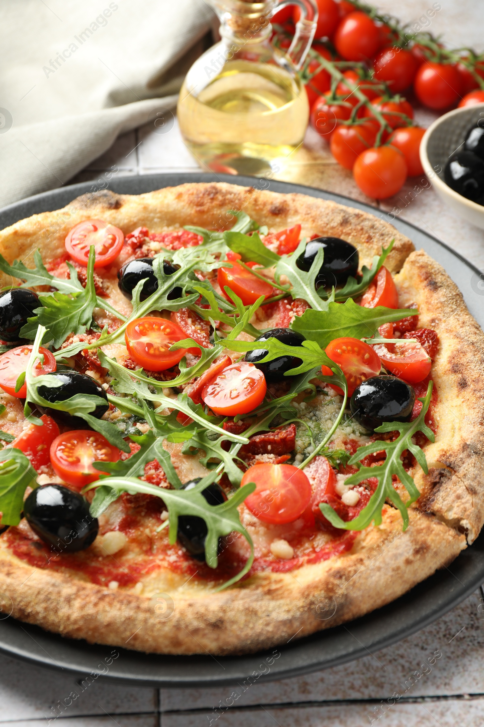 Photo of Tasty pizza with tomatoes, olives and arugula on light tiled table, closeup